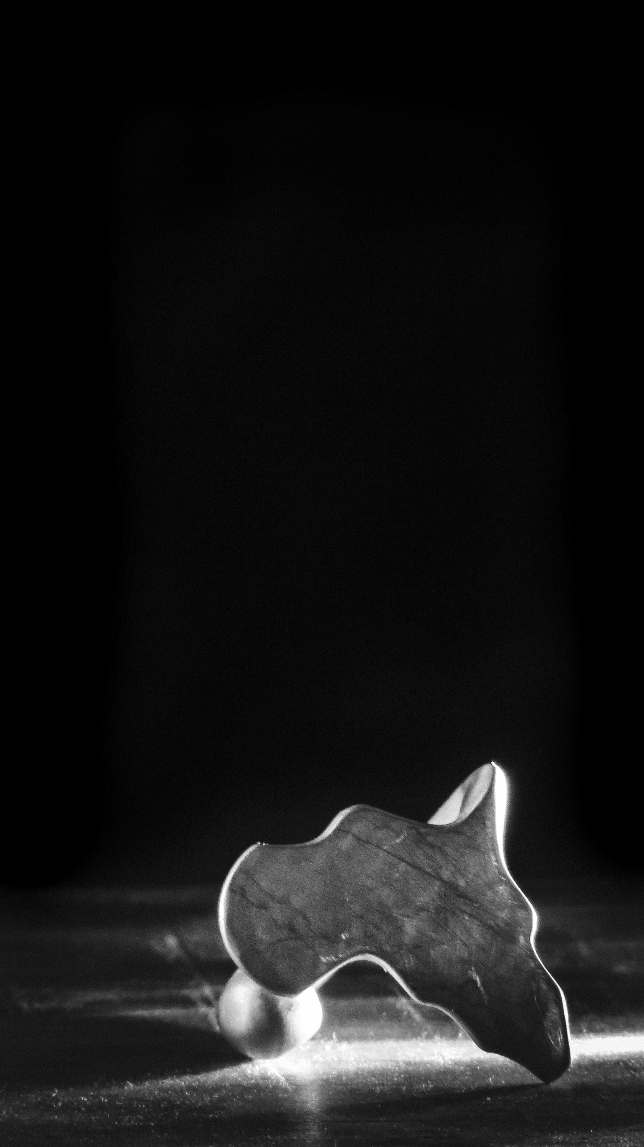 Gua sha stone and pearl on a dark surface