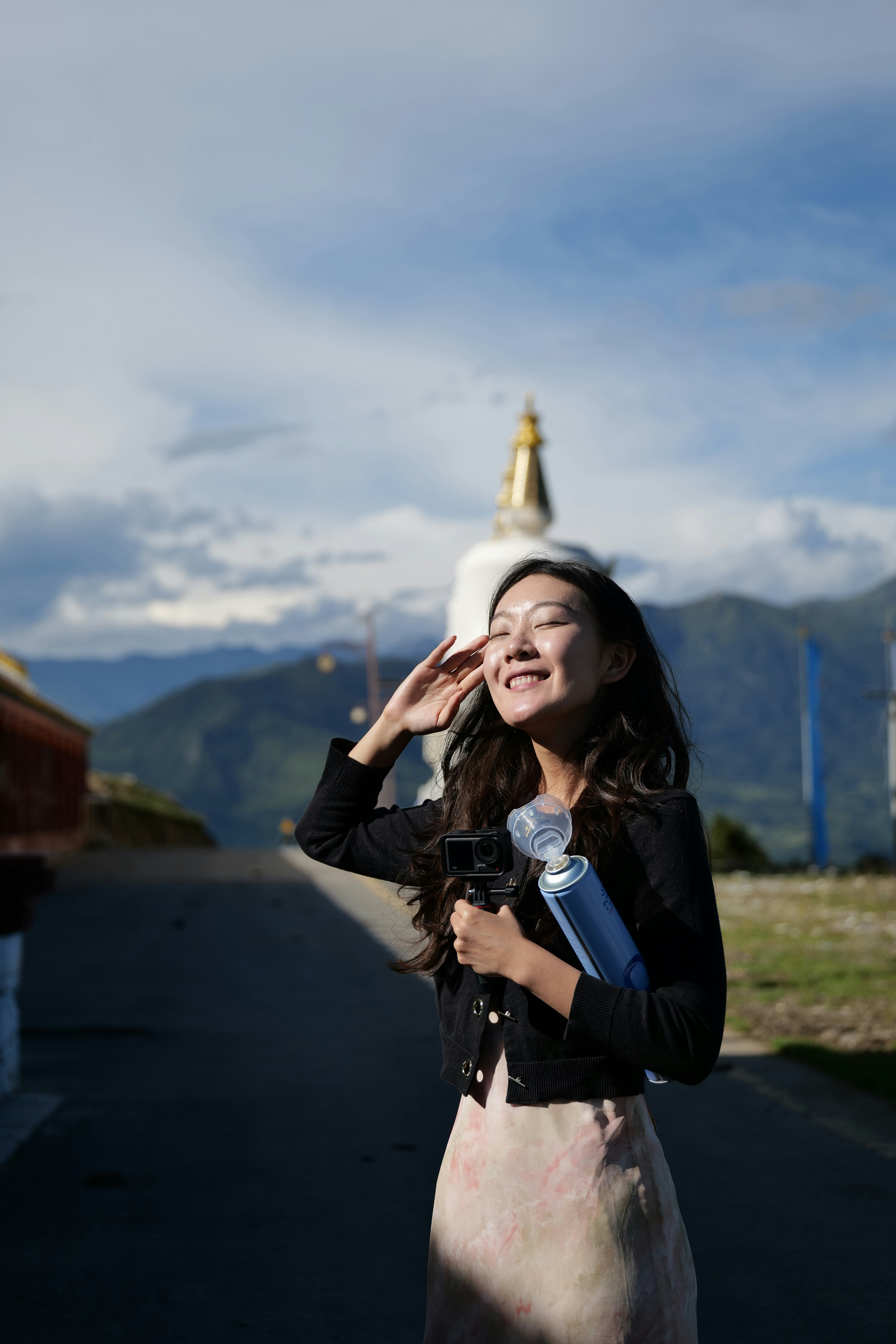 Donna che tiene la bottiglia vicino allo stupa con le montagne