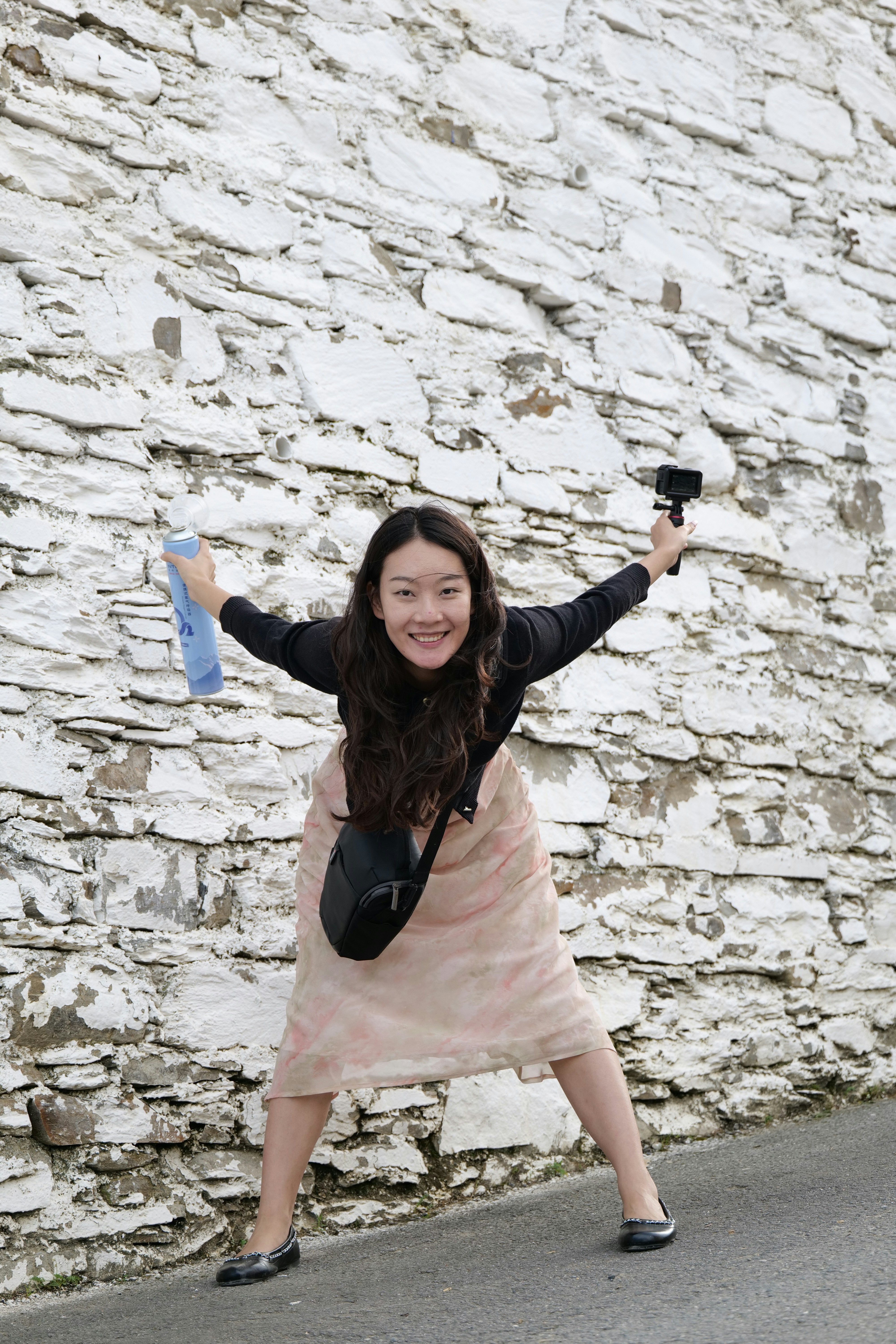 Young woman with camera and water bottle by wall