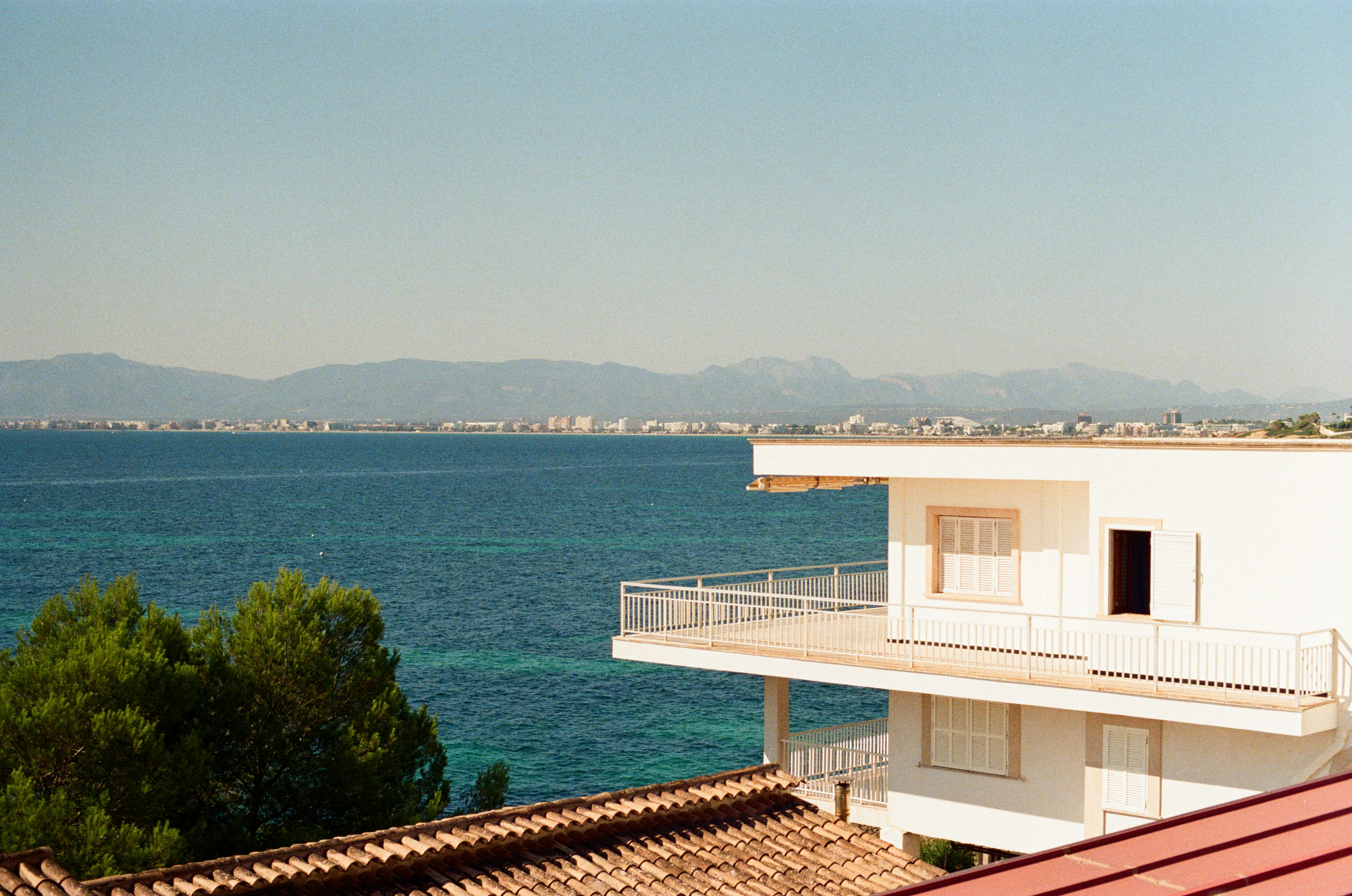 White building overlooks turquoise ocean and distant coastline