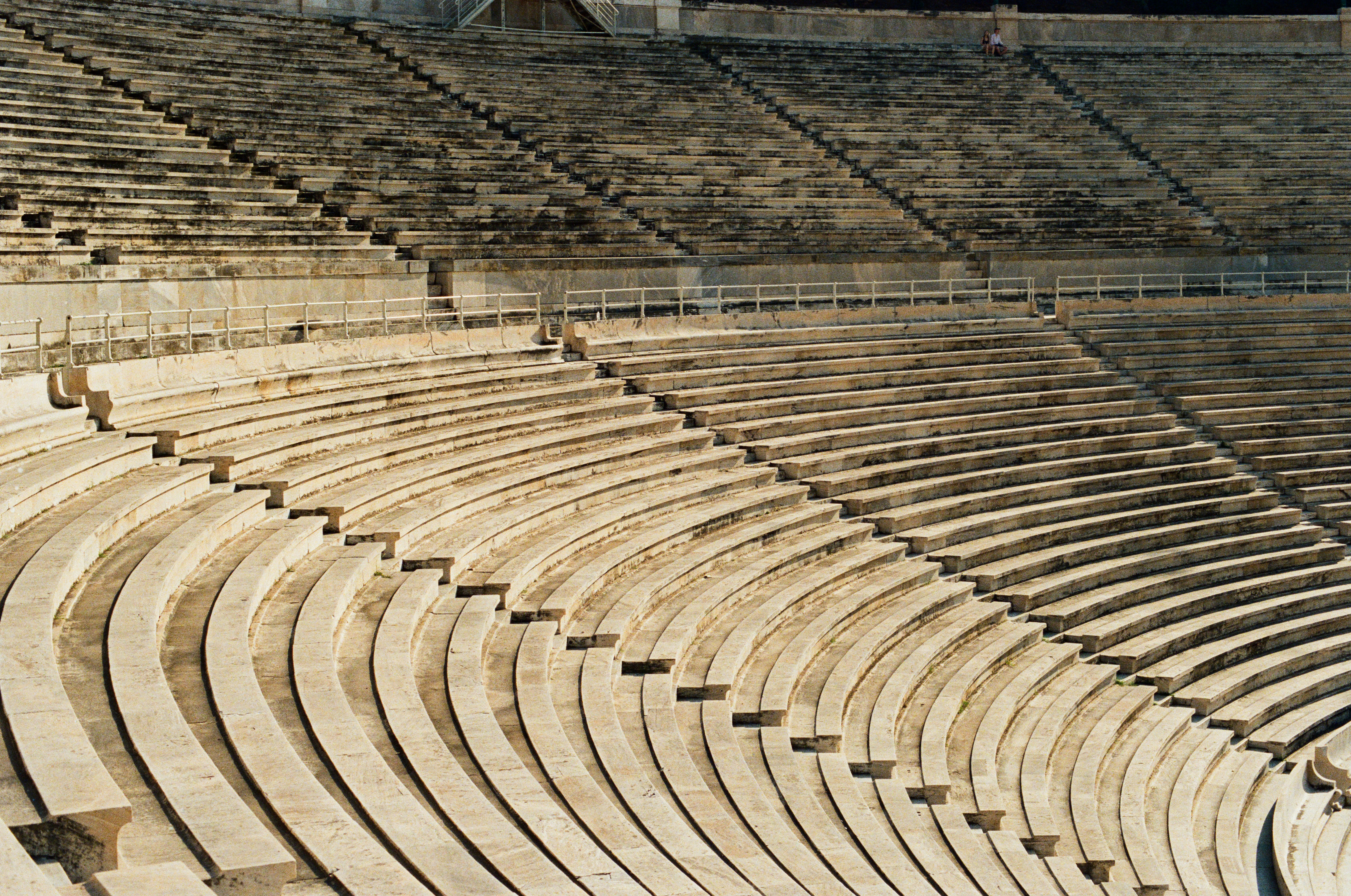 Empty stone stadium seating under a bright sky