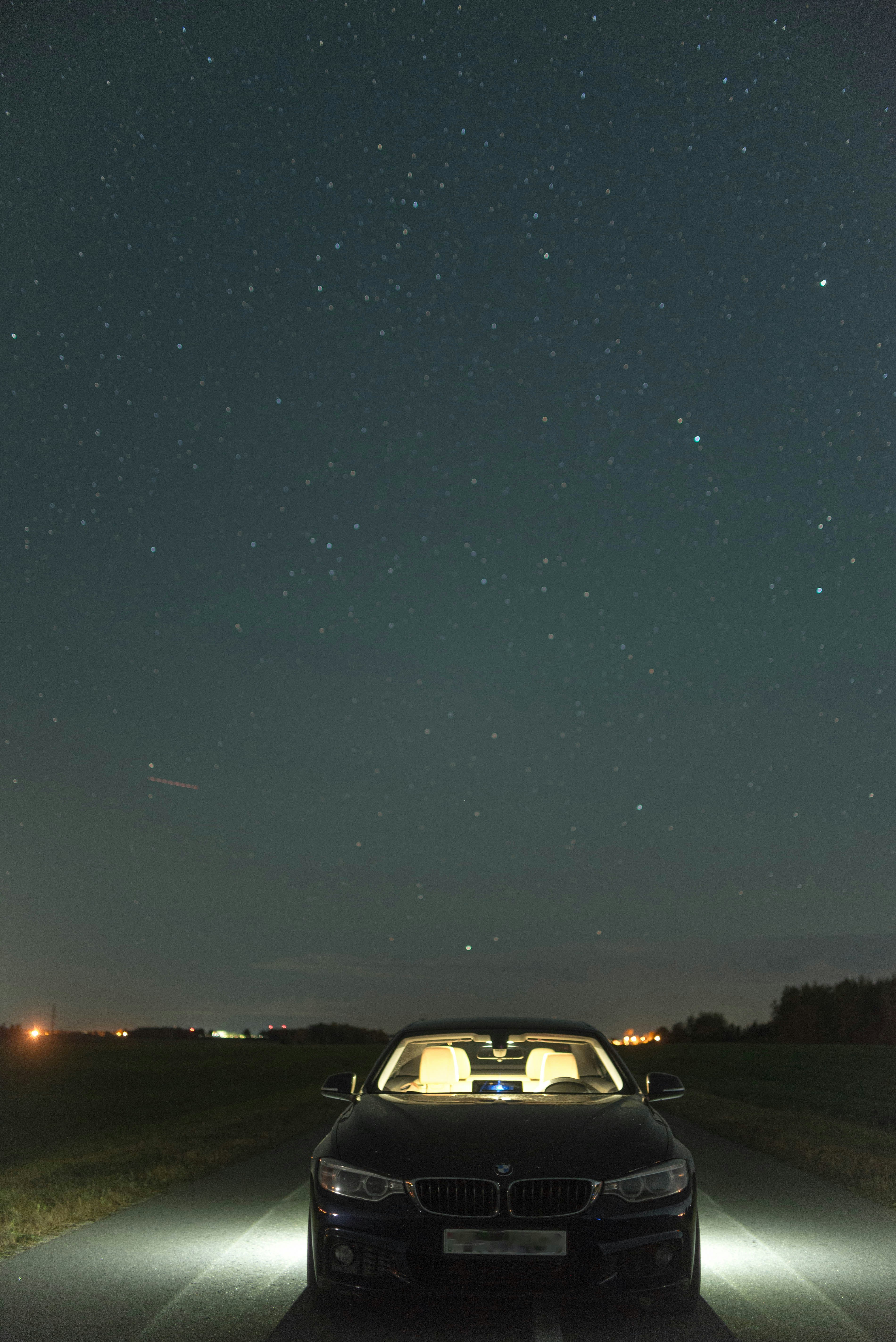 A black car parked under a starry night sky.