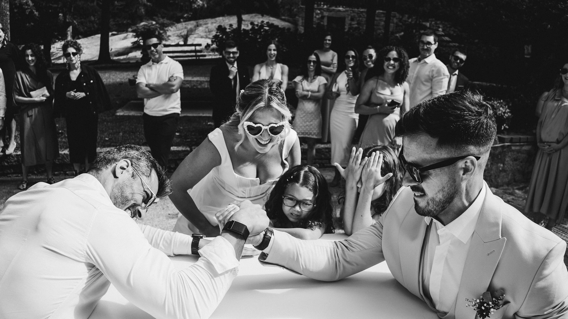 Wedding guests watch arm wrestling match at reception.