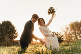 Newlyweds embracing in a sunlit grassy field