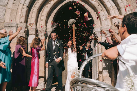 Newlyweds showered with petals leaving church.