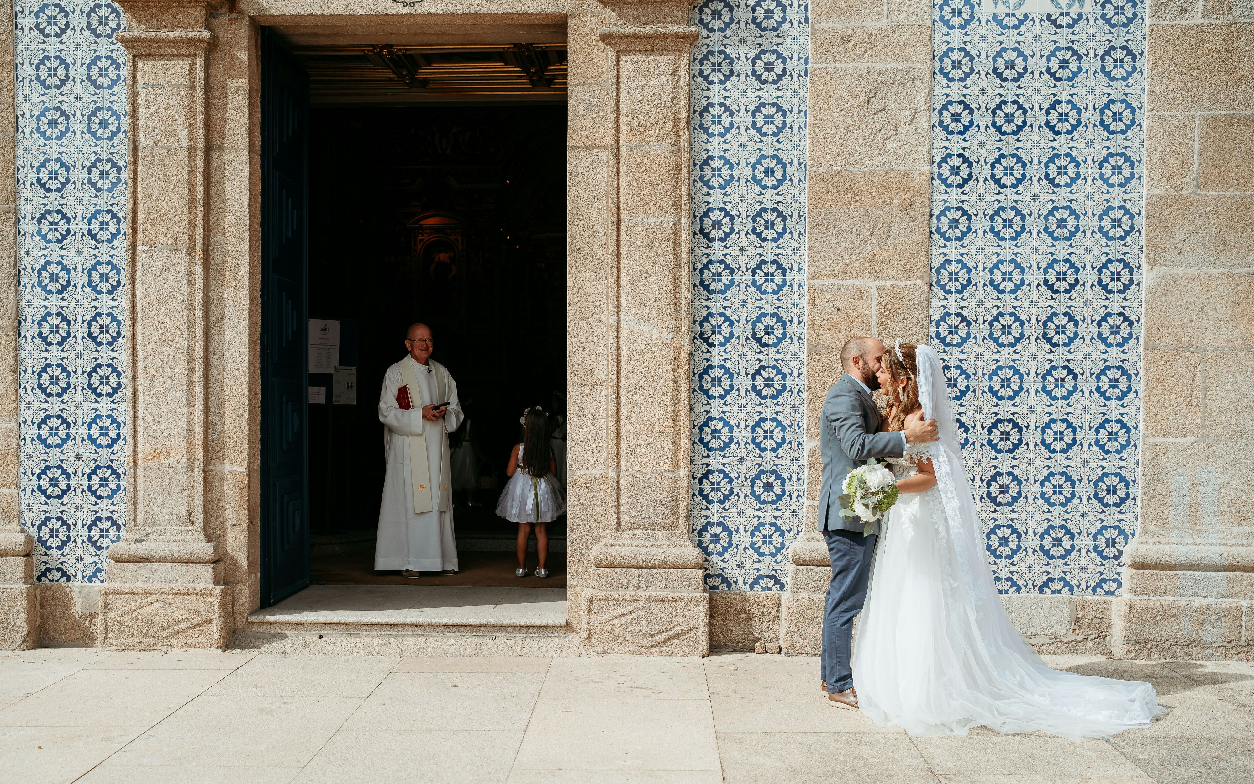 Bride and groom kissing outside a church entrance.