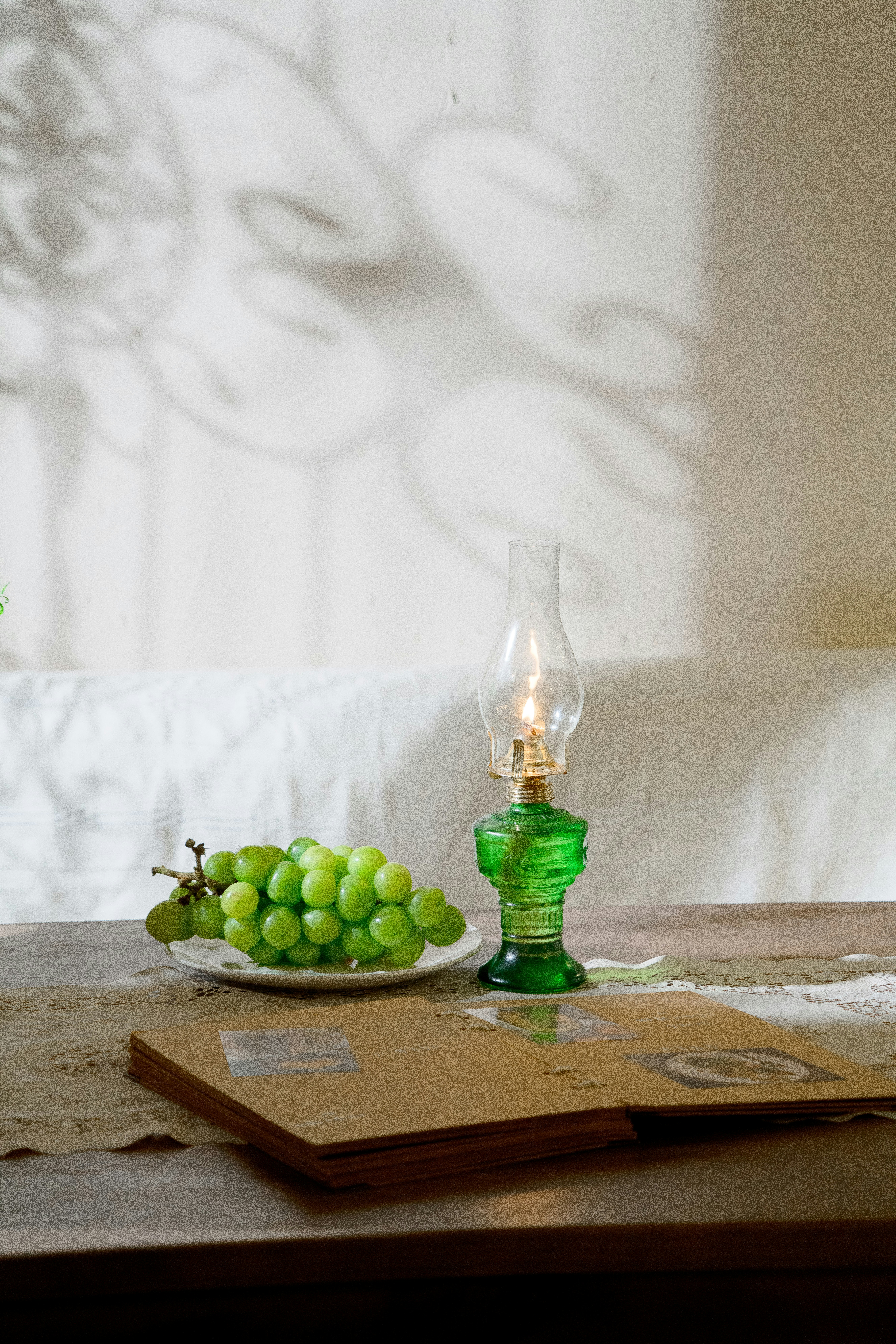 Uvas verdes junto a una lámpara de aceite vintage y un álbum.