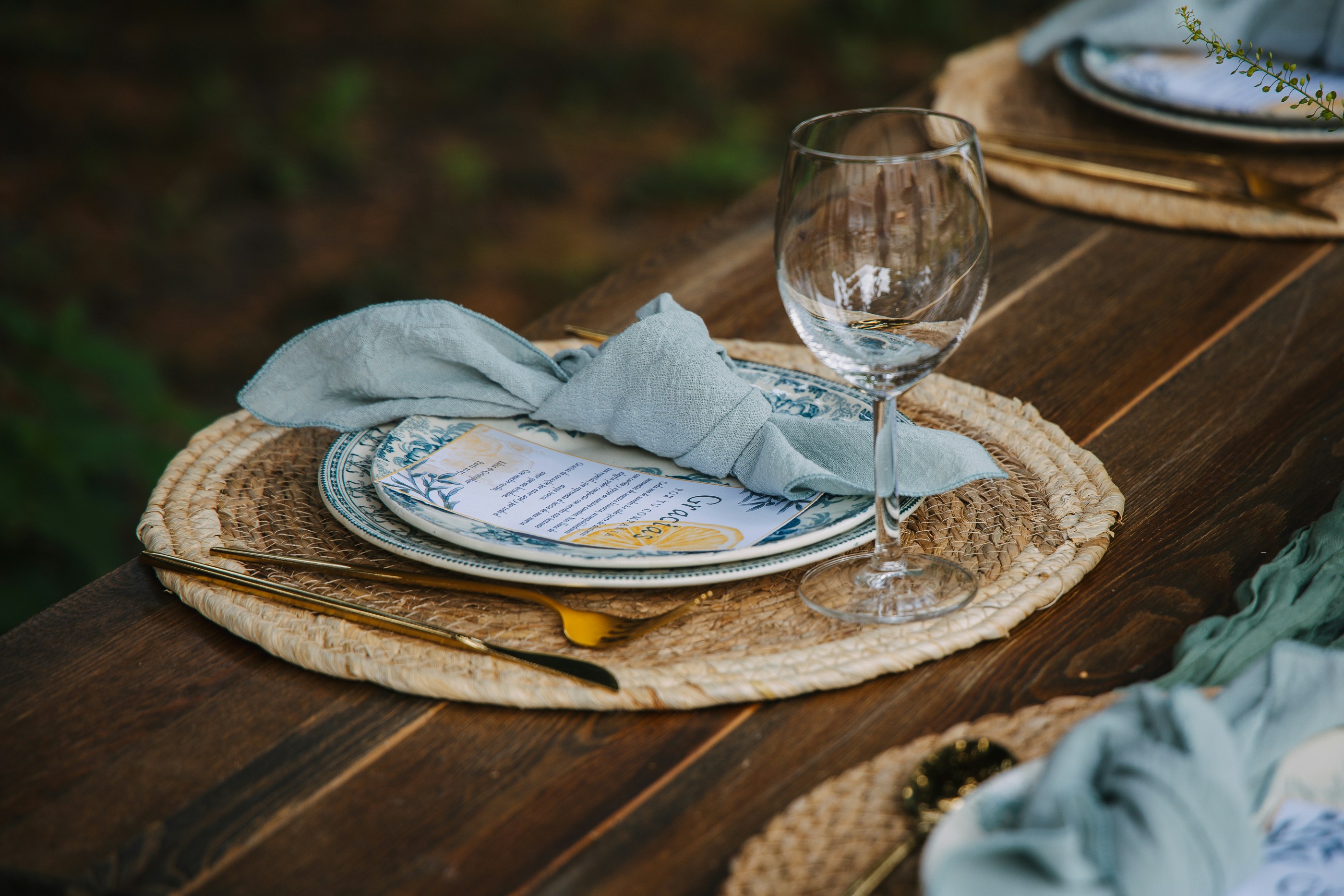 Outdoor table setting with plates, wine glass, and cutlery.
