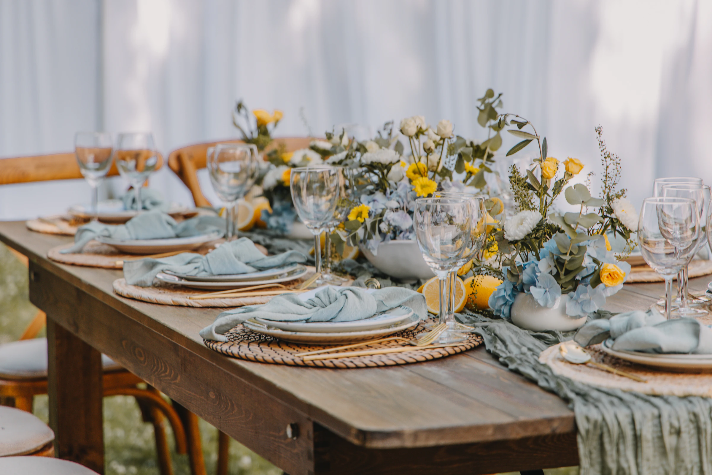 Outdoor celebration table arranged with flowers, glassware, and reusable place settings