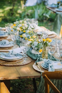 Outdoor table setting with floral centerpieces and blue napkins