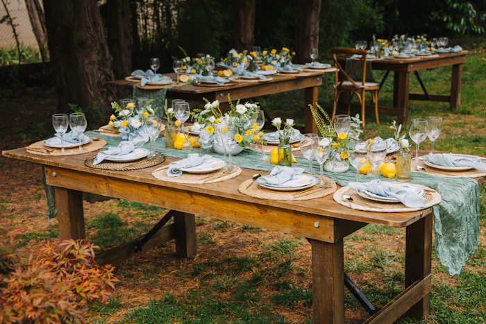Longue table en bois dressée pour un dîner dans un jardin arboré