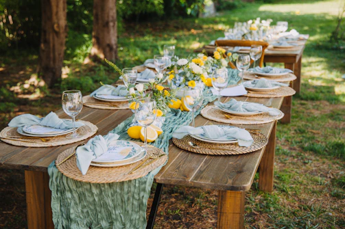Outdoor dining table set for a party with floral decorations.
