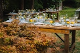 Outdoor tables set for a festive gathering with floral arrangements.