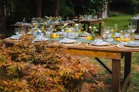 Outdoor tables set for a festive gathering with floral arrangements.