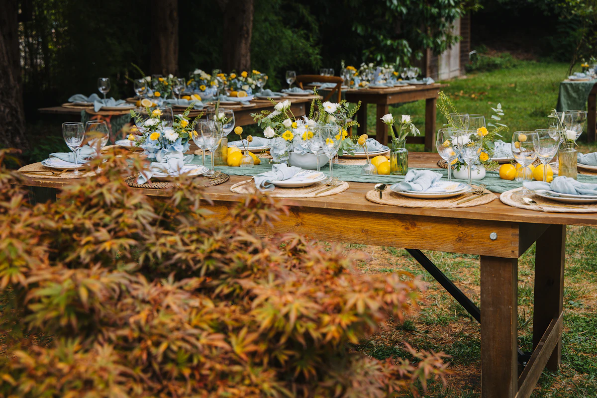 Long outdoor table set for an evening dinner with floral arrangements.