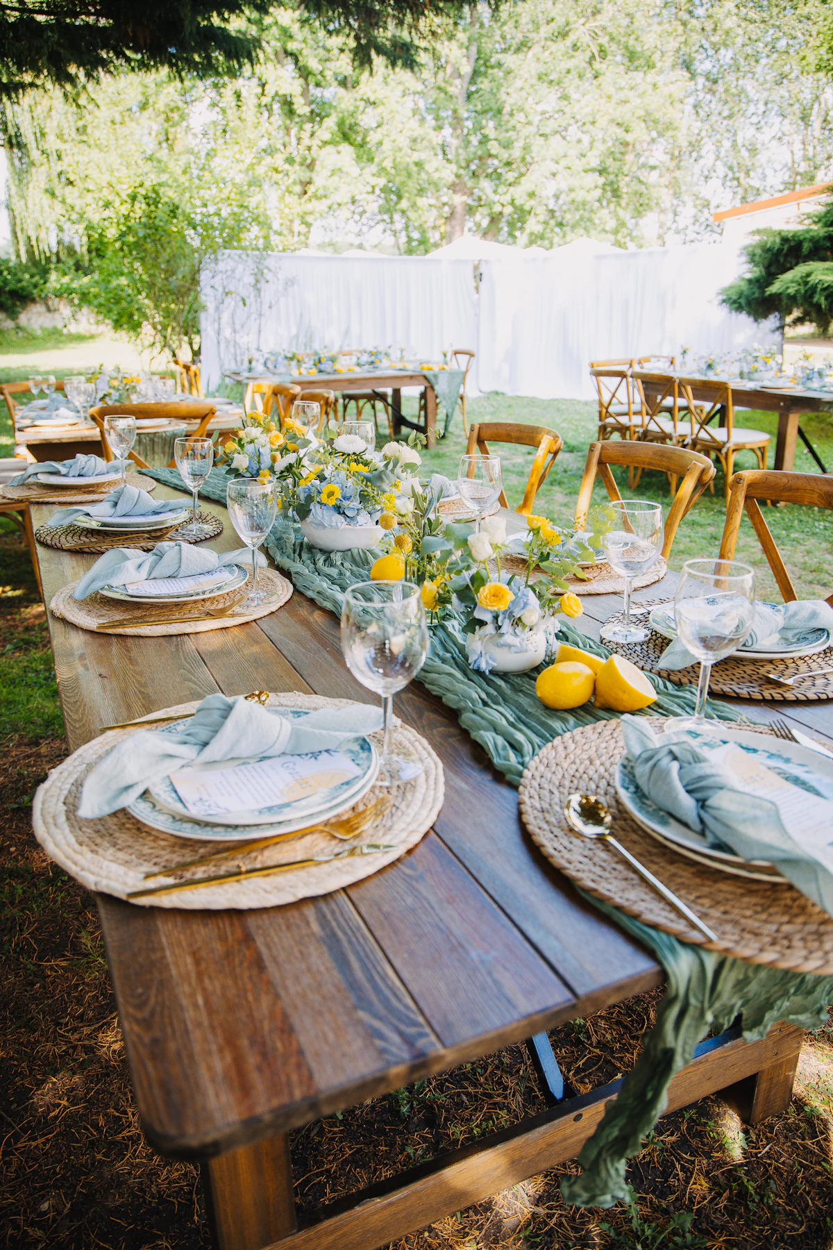 An outdoor wedding reception table styled with yellow flowers and fresh citrus