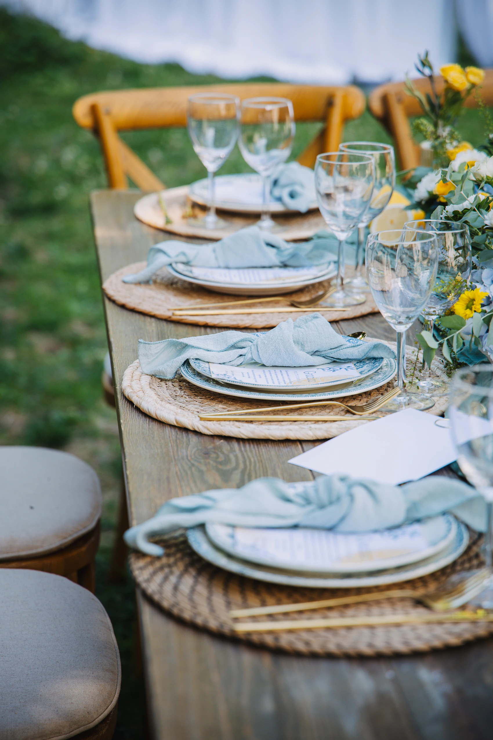 Elegant outdoor place settings with glassware, flowers, and folded napkins