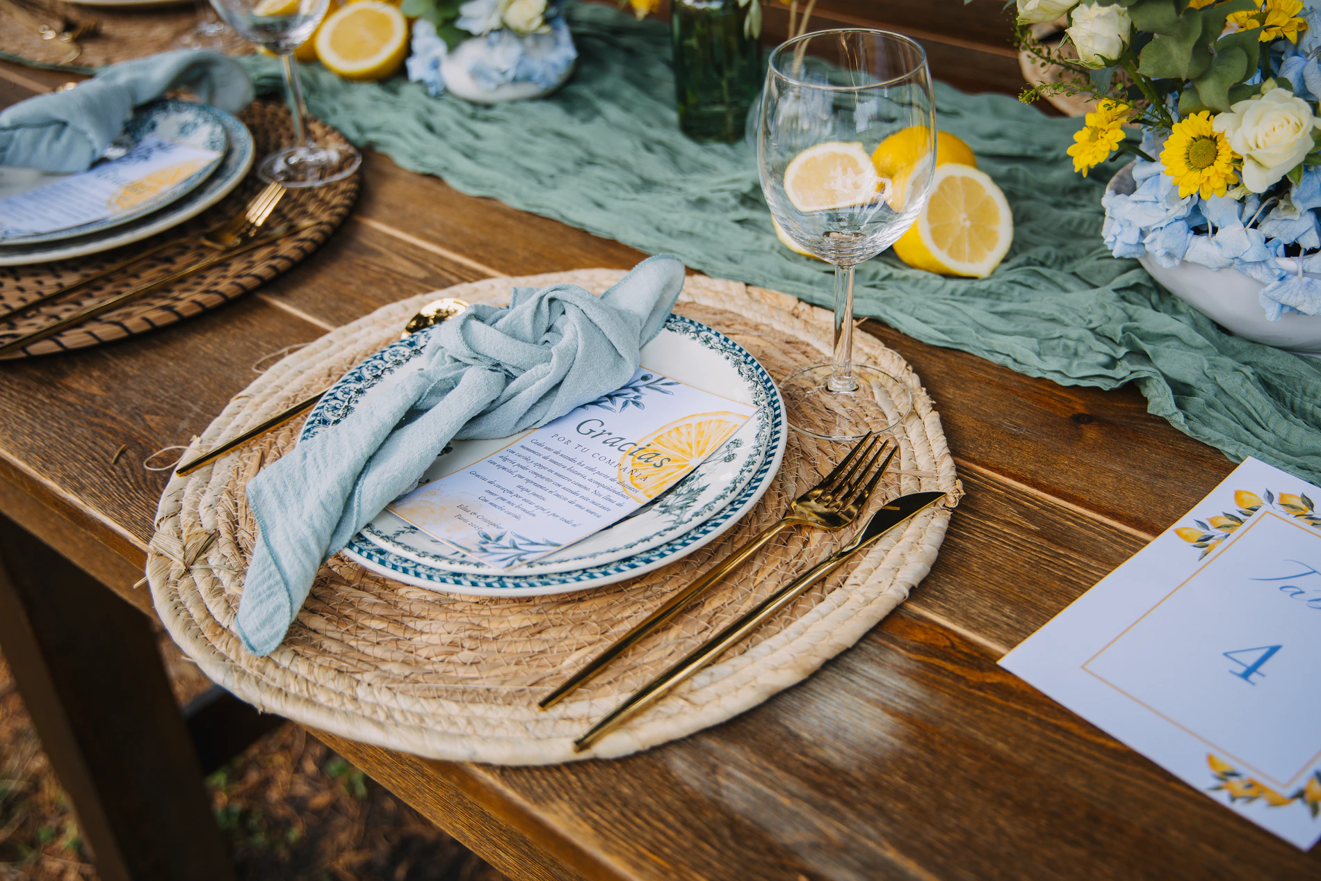 Elegant table setting with blue napkins, lemons, floral accents, and glassware