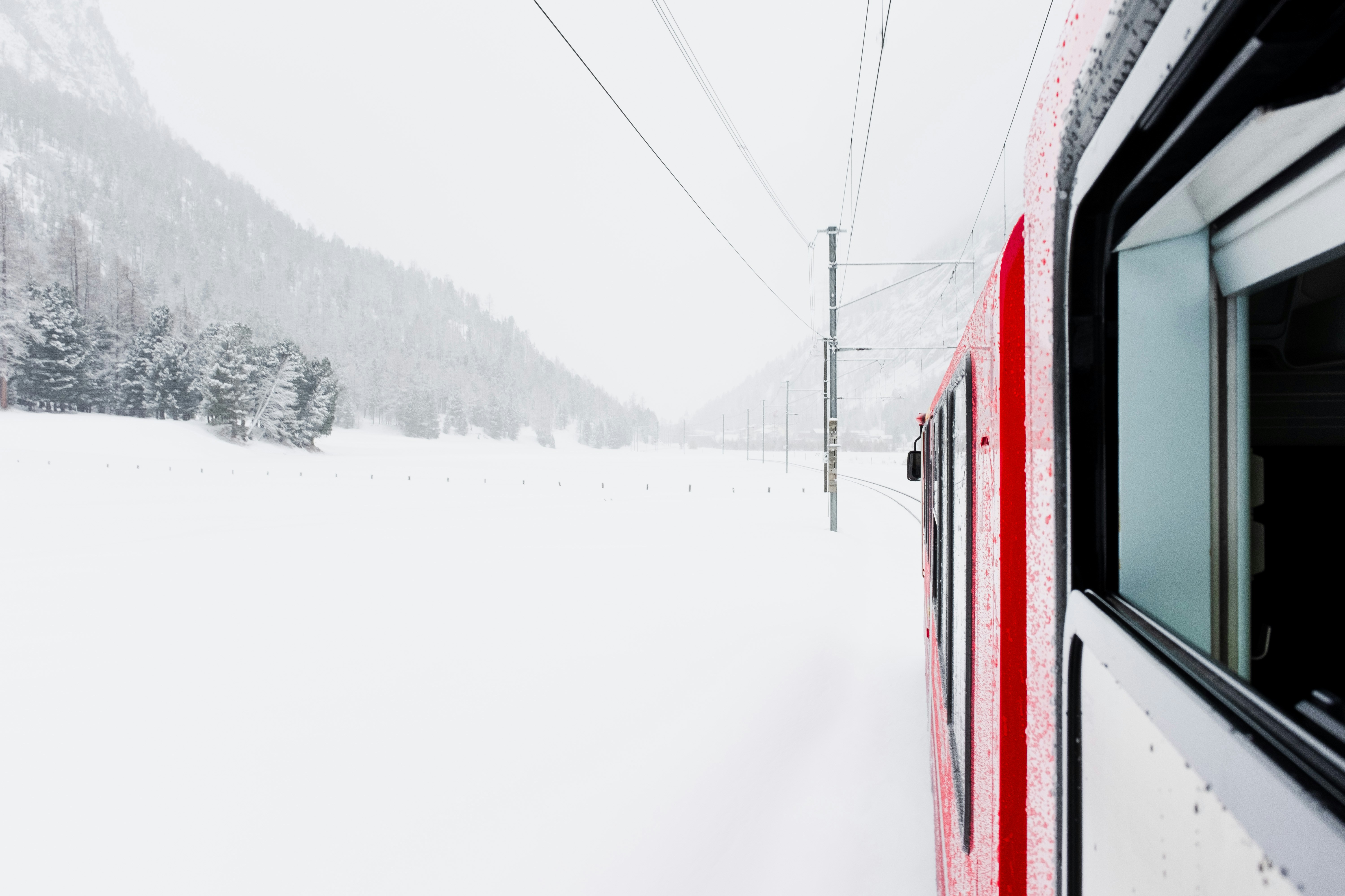 Red train traveling through a snowy landscape