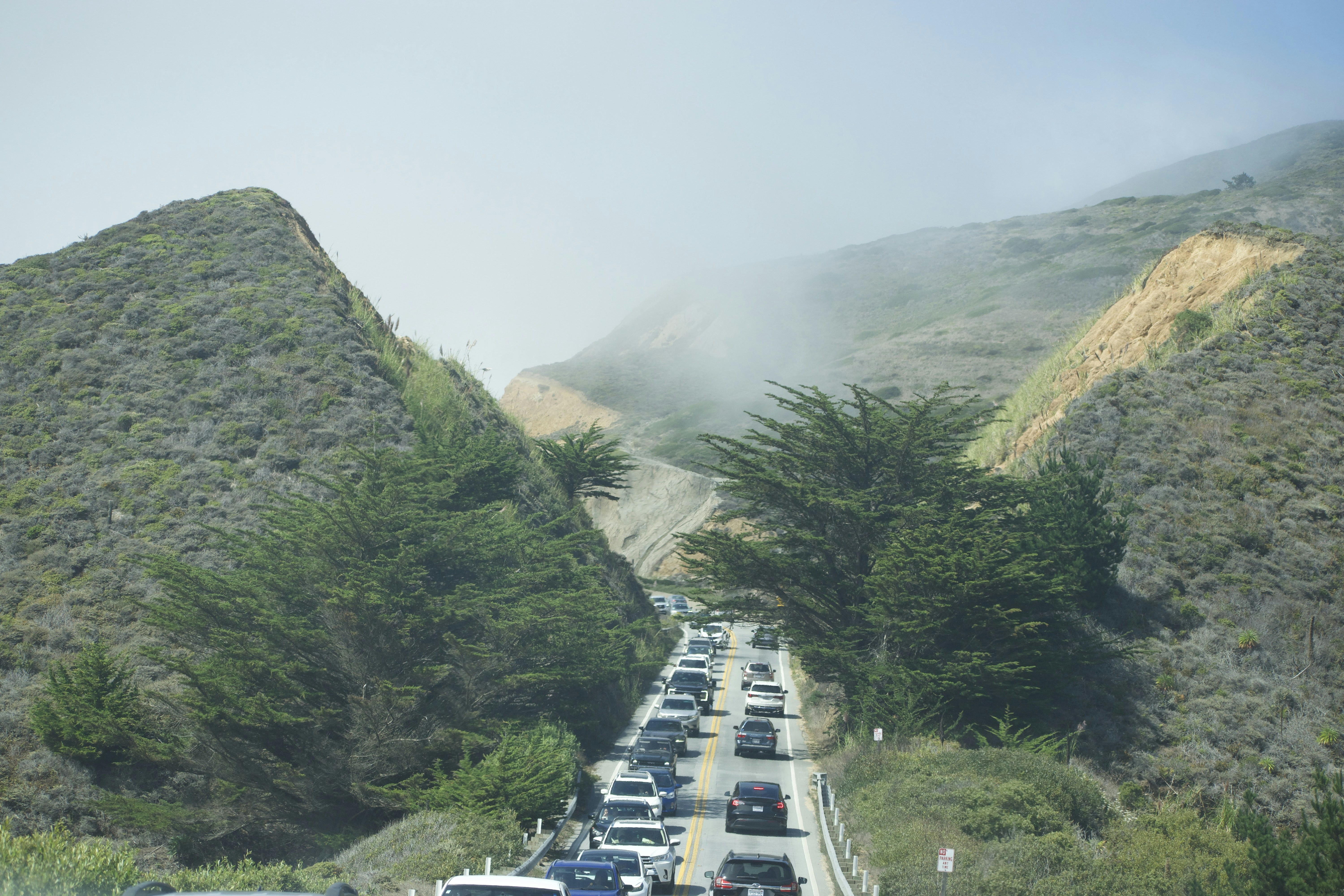 Cars backed up on a winding road through hills.