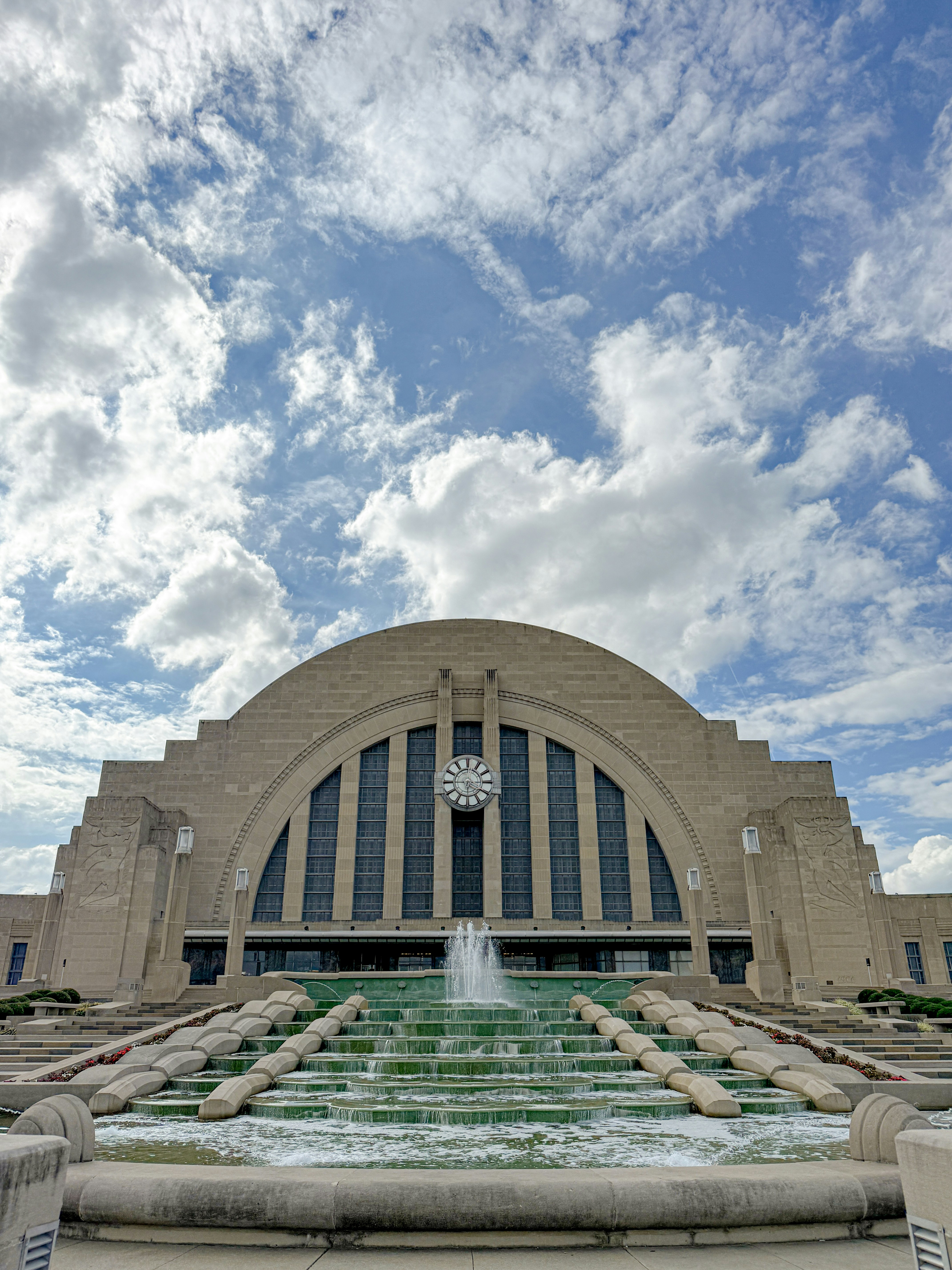 Großartiges Art-Deco-Gebäude mit Brunnen und bewölktem Himmel.