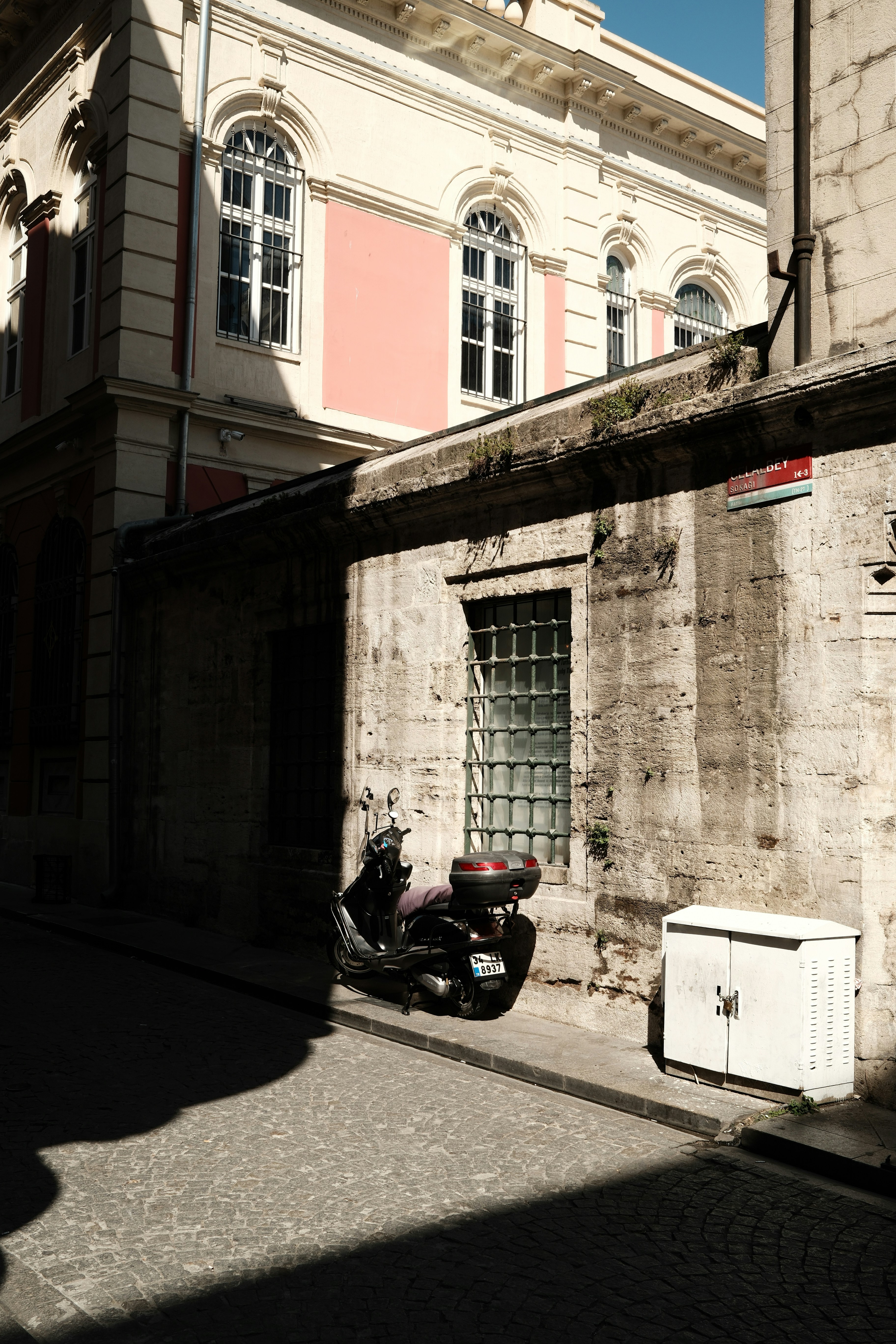 Scooter parked on a sunlit street next to building