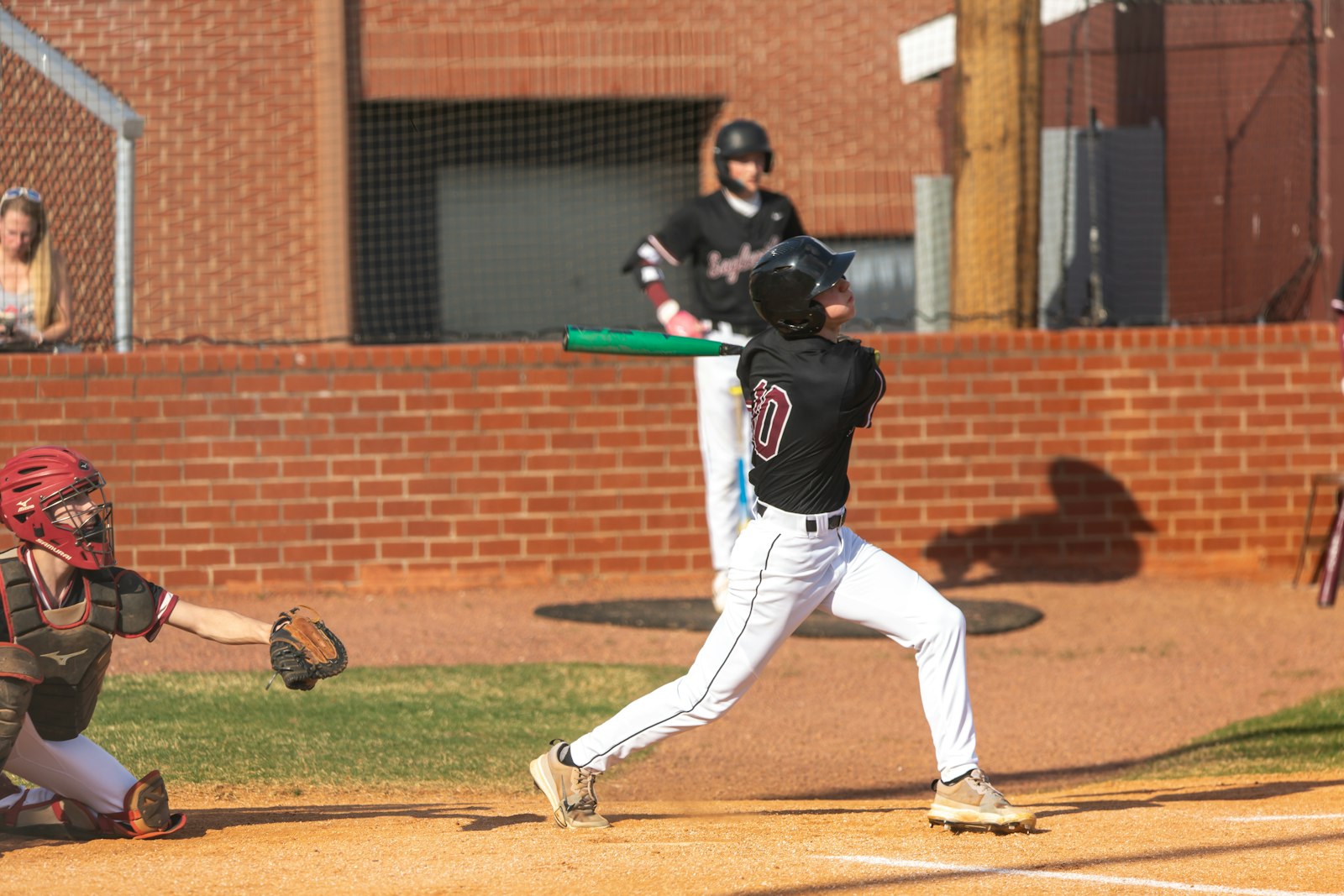 A baseball batter swings at a pitch with the catcher set behind home plate — the kind of late-inning at-bat where calf and hamstring cramps decide the game.