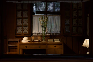 Desk with hat, radio, and flowers in room
