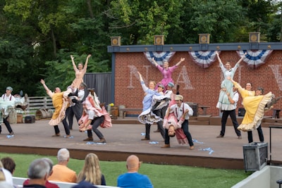 Performers dance on an outdoor stage with audience watching
