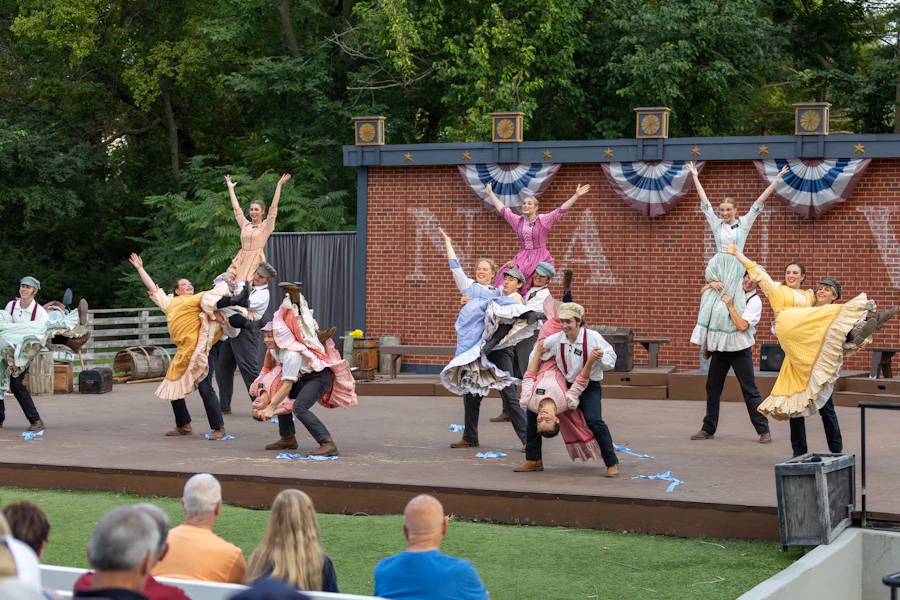Young performers mid-scene on stage as an audience watches