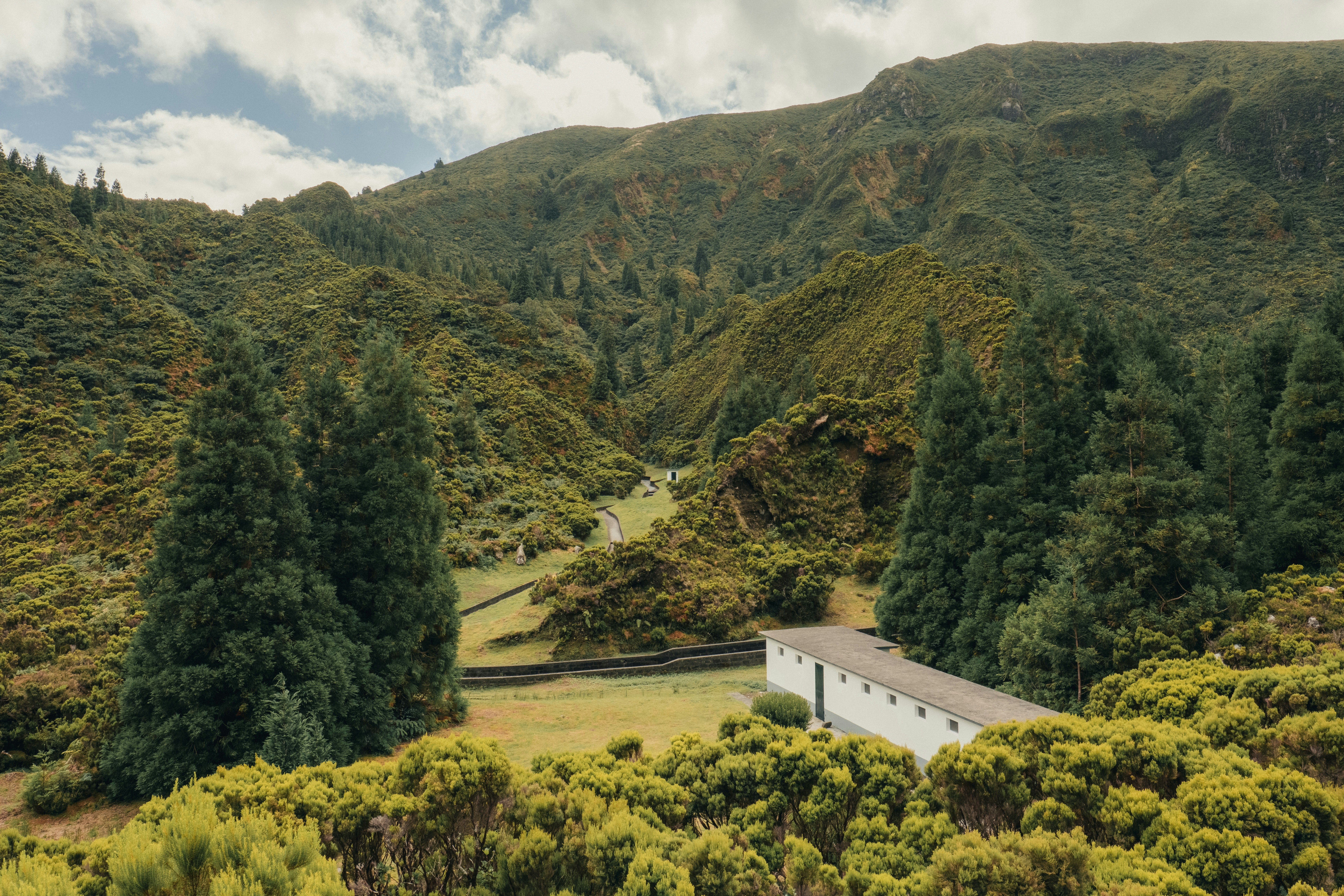 Grüne sanfte Hügel mit einem weißen Gebäude und Bäumen.