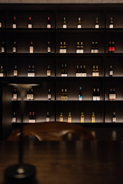 Wine bottles displayed on shelves in a dimly lit cellar.