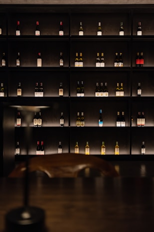 Wine bottles displayed on shelves in a dimly lit cellar.