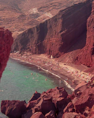 Red sand beach with turquoise water and many people