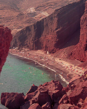 Red sand beach with turquoise water and many people