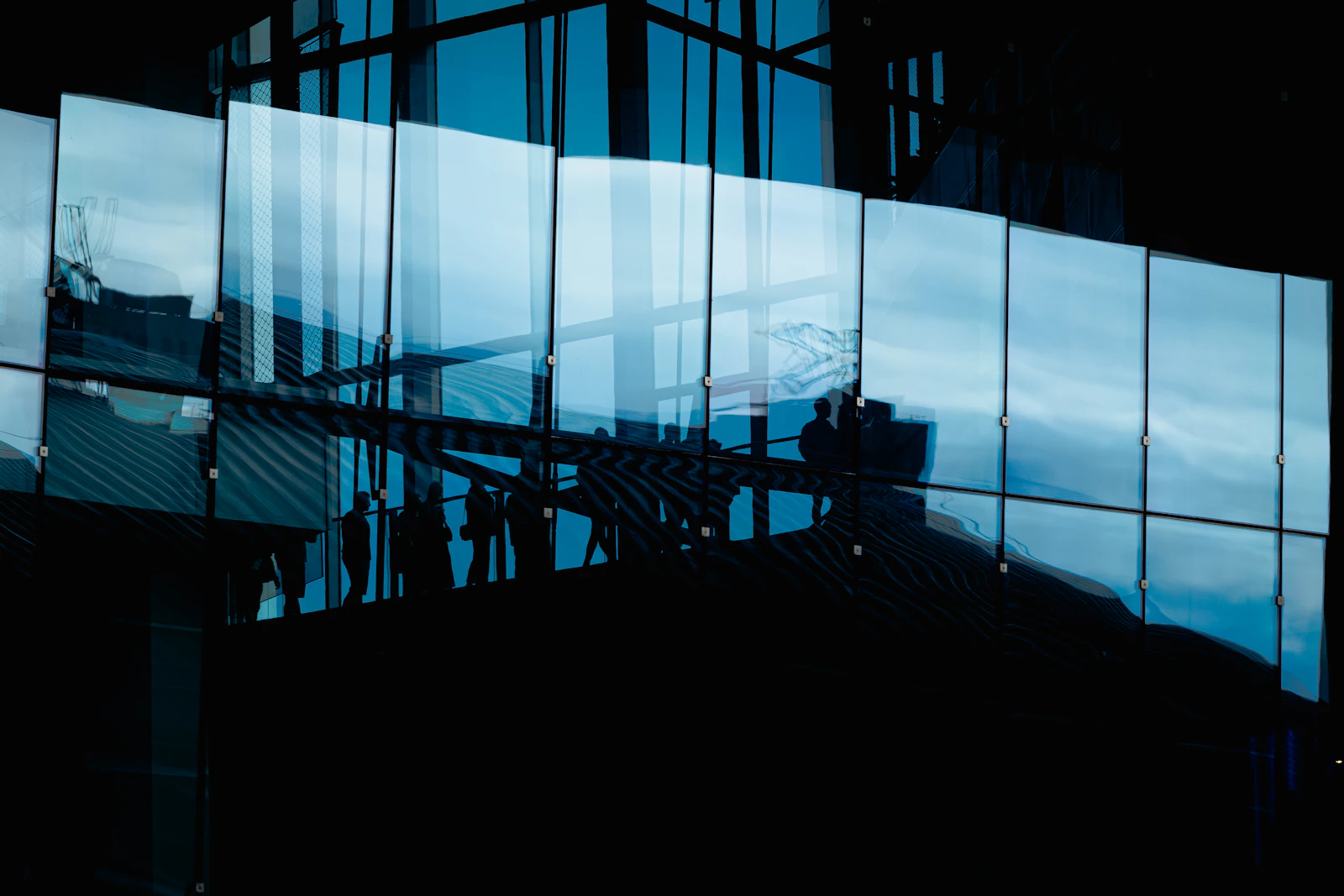 Figures moving through reflected glass architecture, representing adviser relationships after transition
