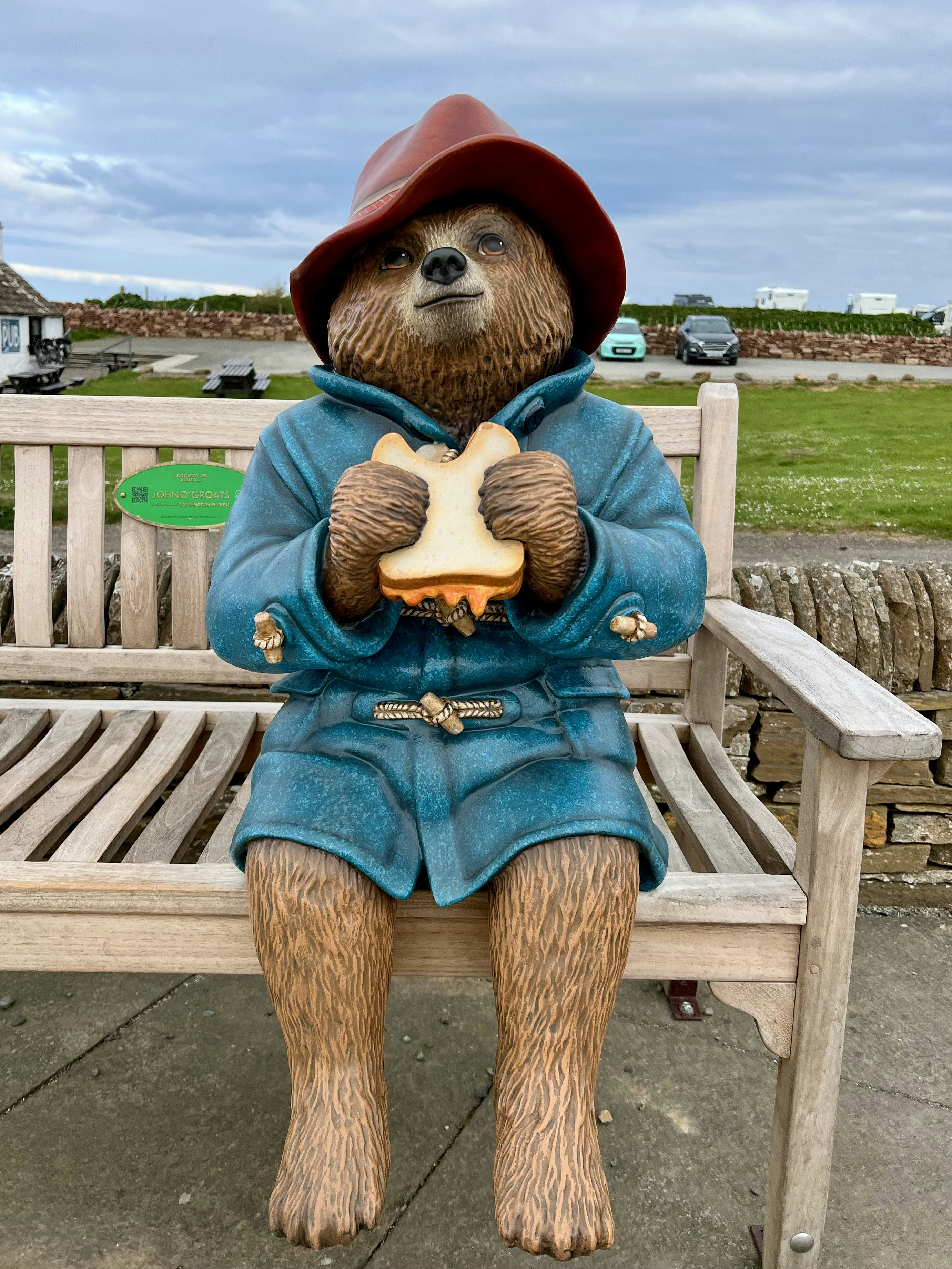 Paddington bear statue sitting on a bench with sandwich