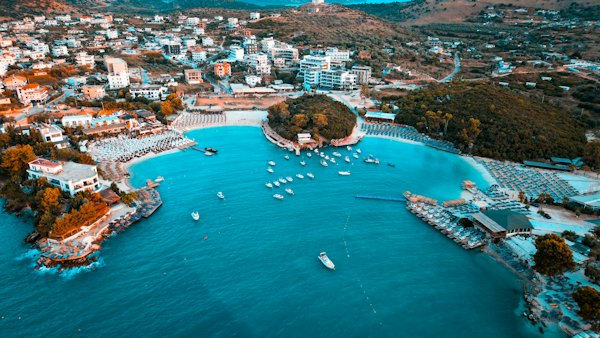 Coastal town with boats in turquoise bay and buildings — Sarandë, Albania