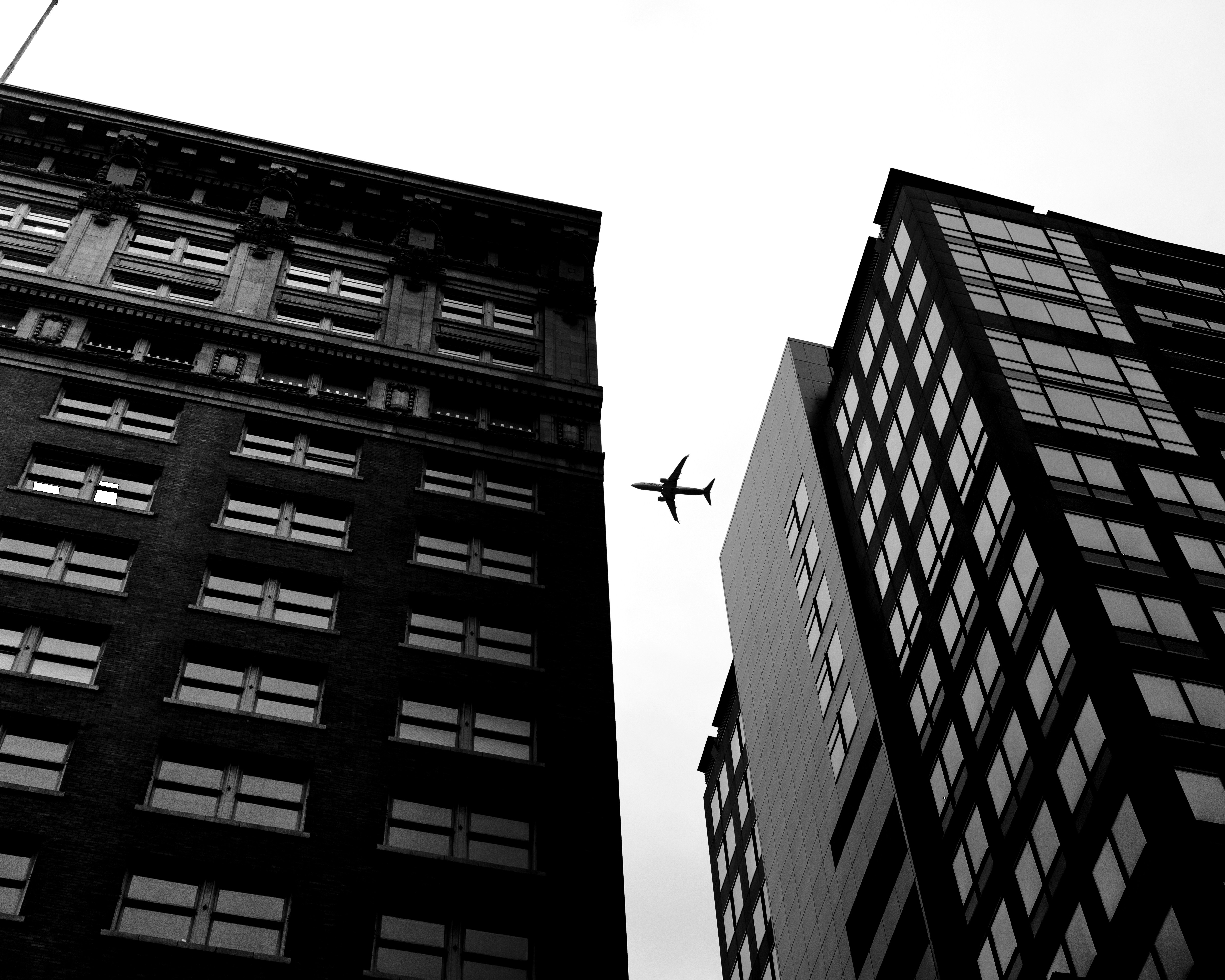 Airplane flying between two tall buildings.