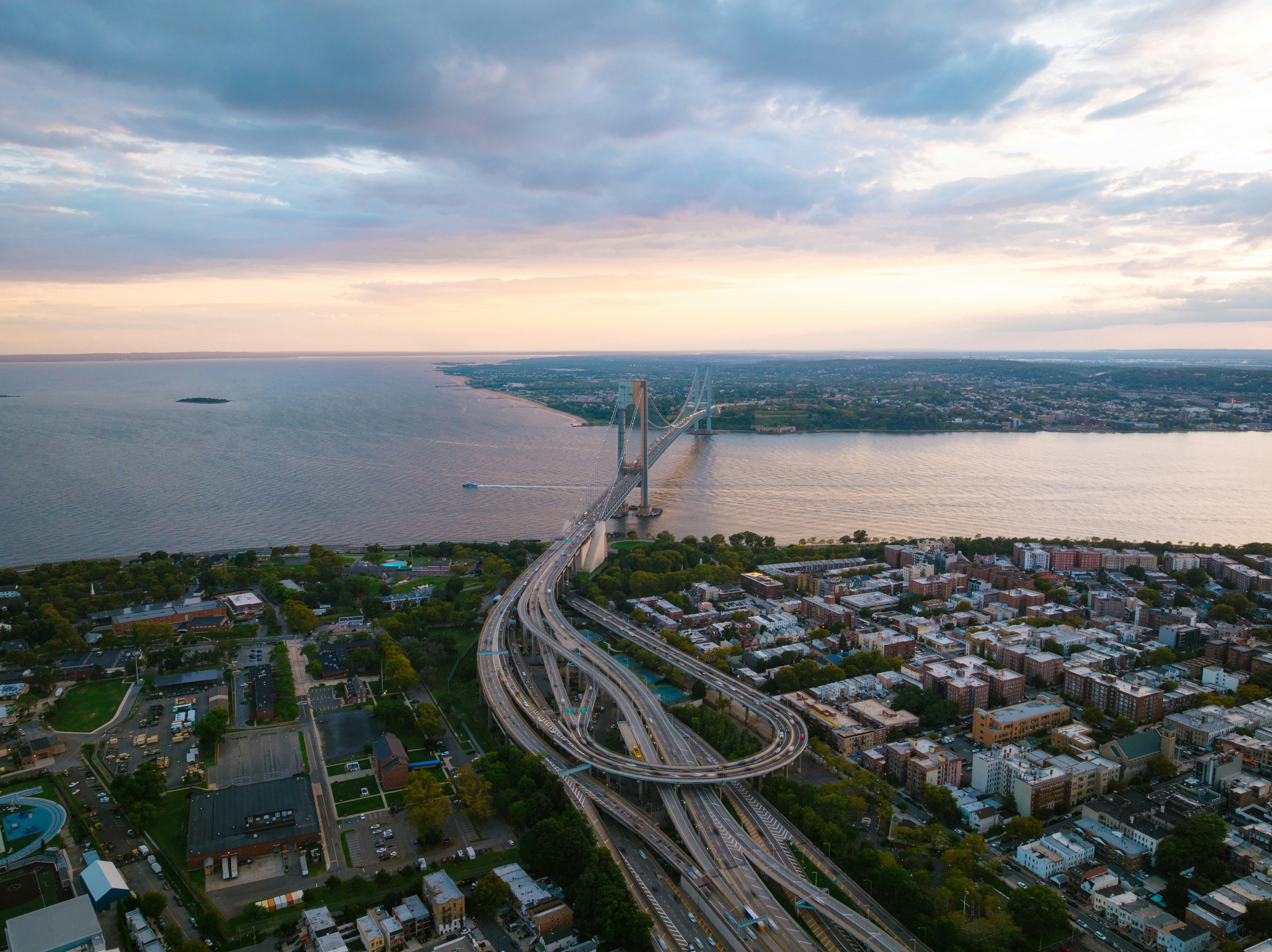 Modern suspension bridge over a wide river at dusk.