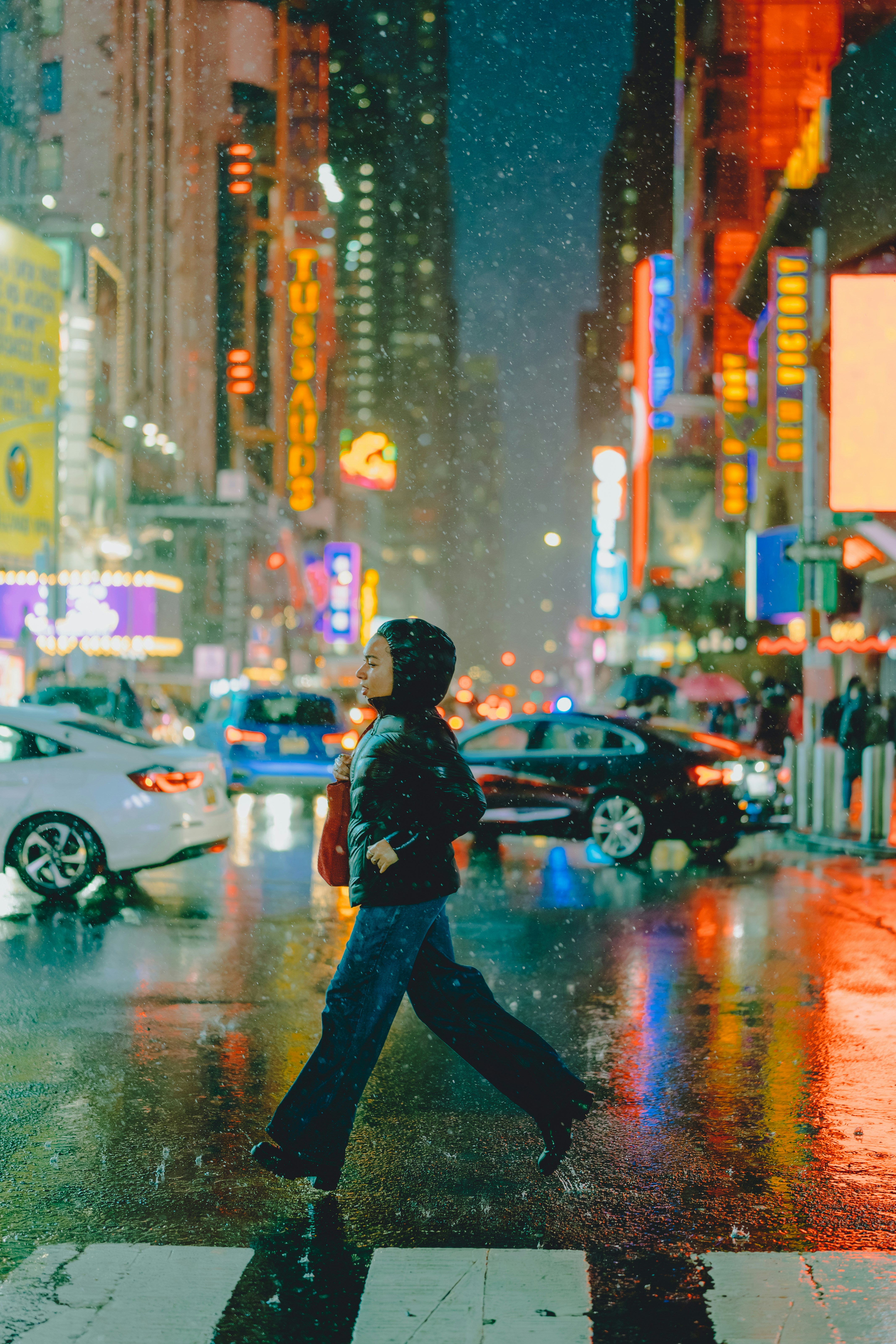 Person crossing a wet city street at night