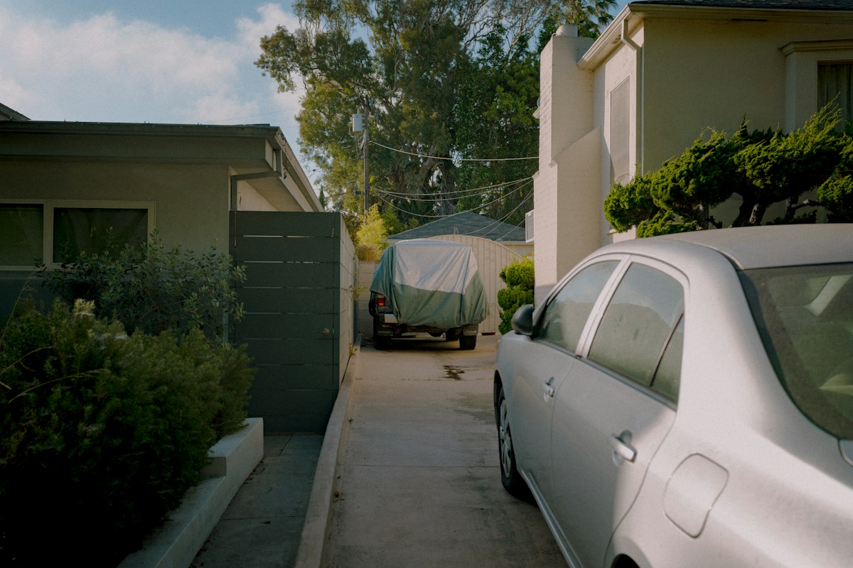 A car loaded with a cooler and sports gear parked in a narrow driveway, ready for a youth sports tournament day.