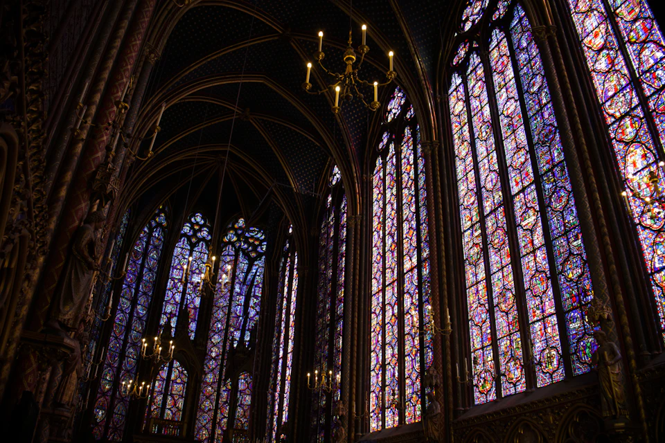 Gothic-style church interior with tall arches, stained glass windows, and intricate ceiling designs above