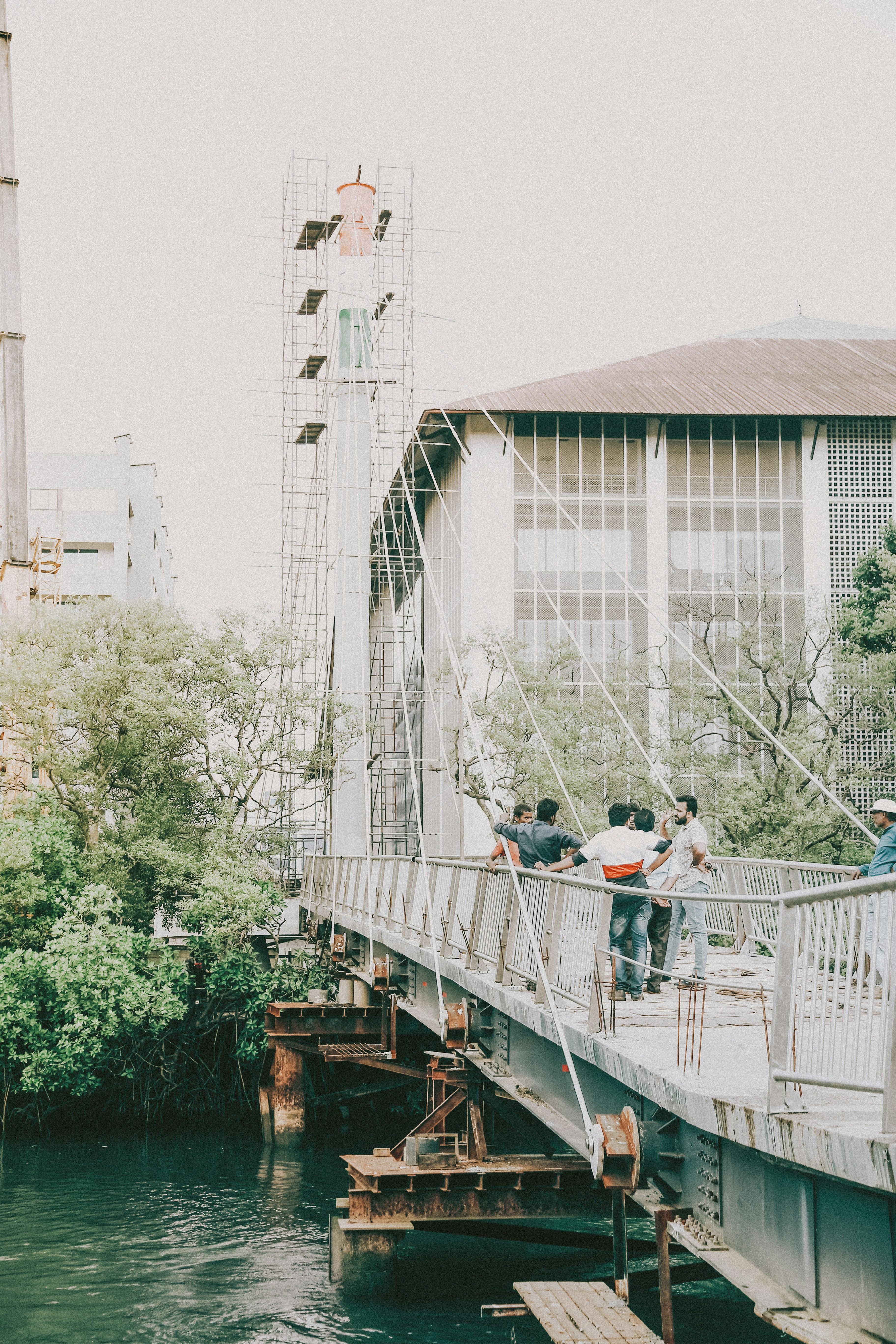People on a suspension bridge near a building.