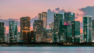 City skyline at dusk with pastel sky and water.