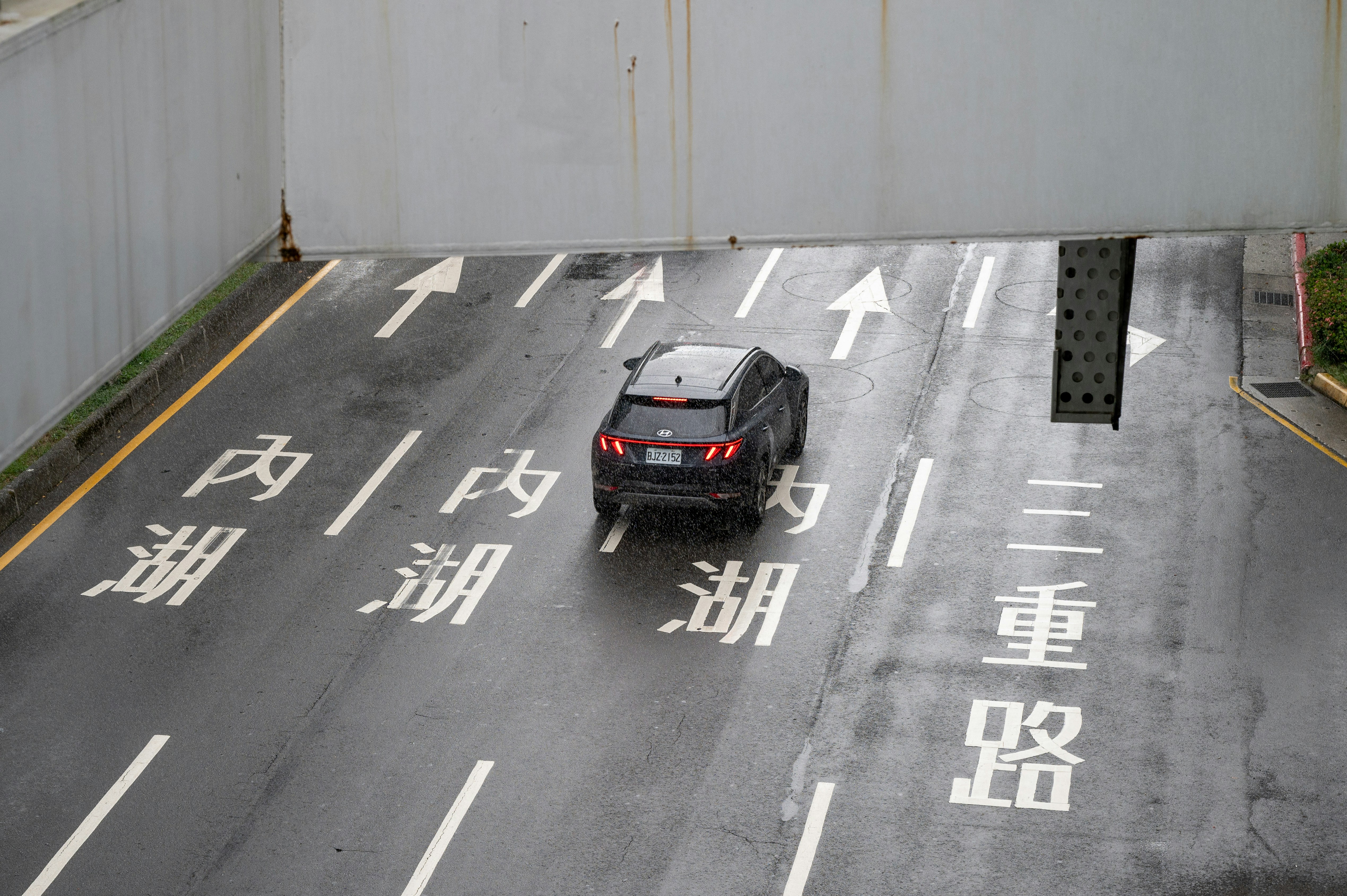 Car driving on wet road with chinese characters.
