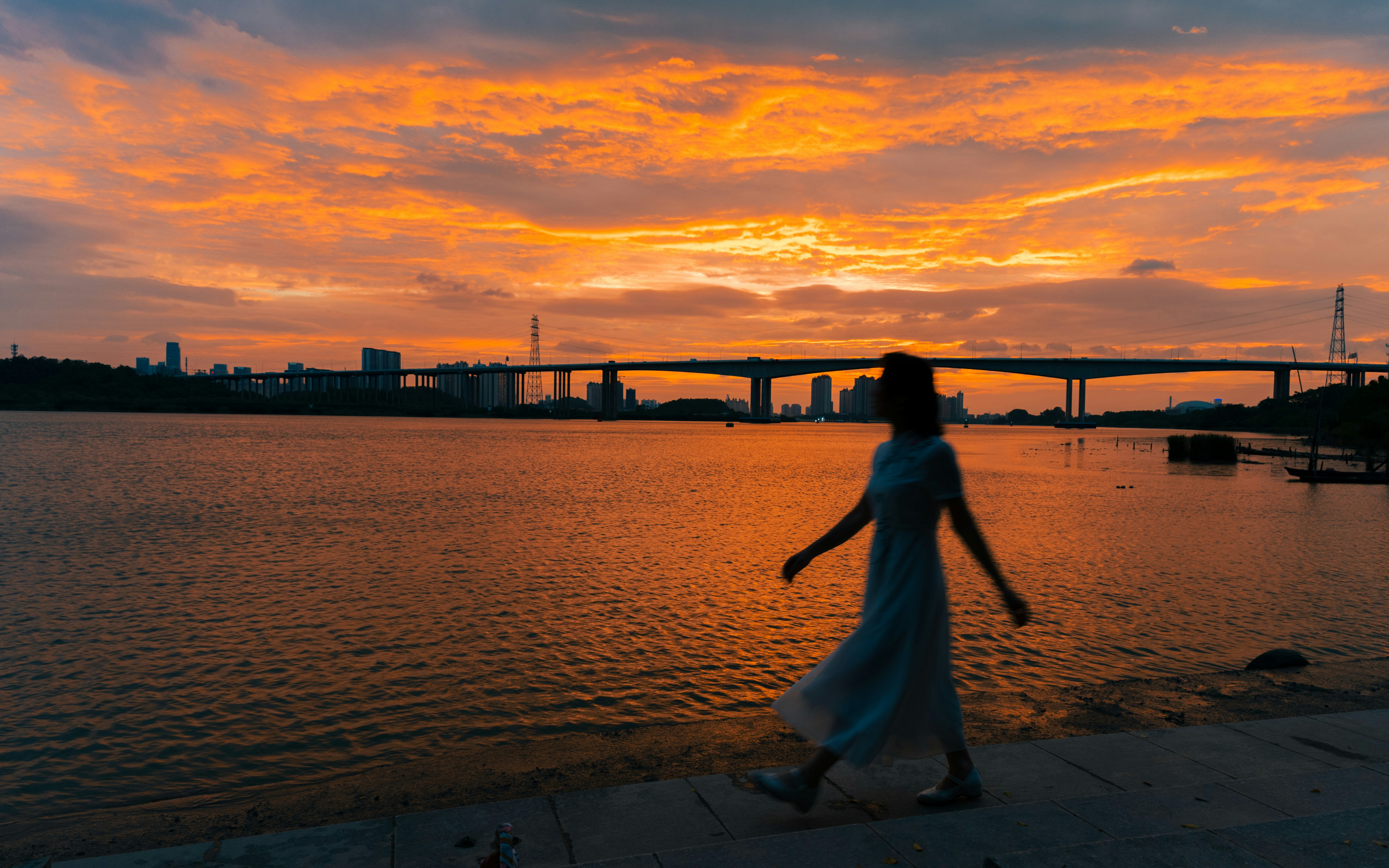 Mujer caminando junto al agua al atardecer