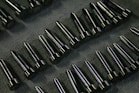 Rows of shiny metal components on a textured surface.