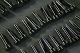 Rows of shiny metal components on a textured surface.