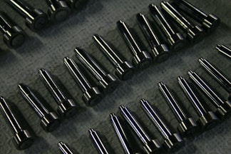 Rows of shiny metal components on a textured surface.
